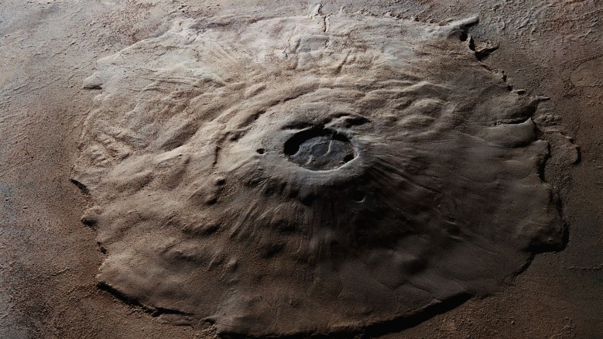 How did researchers come to discover the colossal volcano on Mars with potential glacier ice beneath it?
